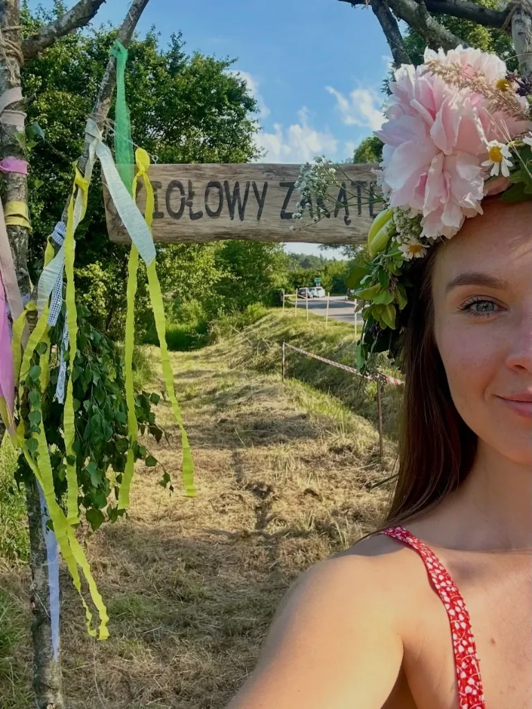 Monika Wierus-Wieczorek w wieńcu z kwiatów przy bramie Ziołowy Zakątek